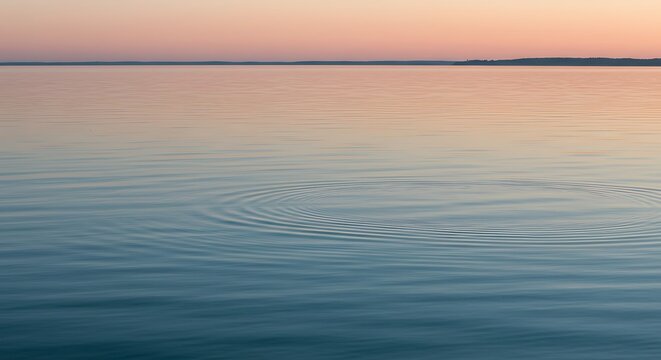 Calm ocean water reflecting soft pastel colors of a serene sunset sky at dusk