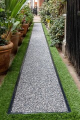 Obraz premium A meticulously crafted gravel path, bordered by artificial turf, winds through a landscaped courtyard.