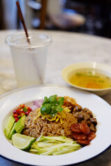 Thai mixed rice and stir fry with shrimp paste and sweet pork and assorted condiments on white dish with lemon juice. traditional of Thai food