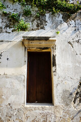vintage antique building with old wooden glass window and green creeper and ivy cover on grunge concrete wall exterior in natural sunlight in Bangkok of Thailand