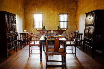 Antique old wooden furniture of Chinese style in vintage and rustic grunge concrete wall in dining room with natural sunlight in Bangkok of Thailand