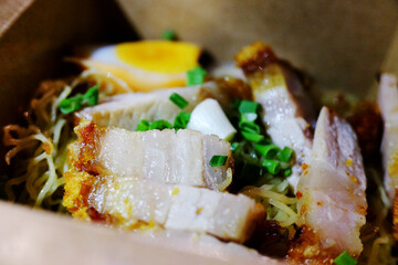 Fresh delicious crispy pork noodles in paper box package on street food of Thailand