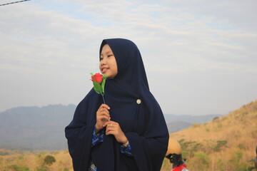 muslimah girl holding flower and smiling