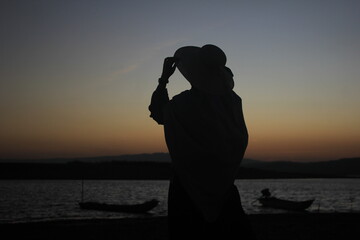 muslimah woman traveling to beach, enjoy the sunset, orange colour