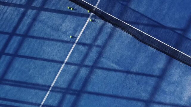 Aerial drone video descending over a blue padel court with tennis balls A Modern Sport