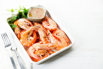 Grilled shrimps with spicy sauce in a white tray.