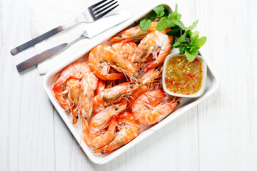 Grilled shrimps with spicy sauce in a white tray.