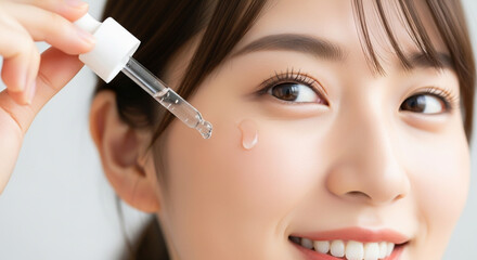 スポイトで美容液（セラム）を塗る笑顔の若い日本人女性