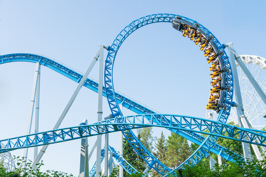 Roller coaster Ride against blue sky. Roller coaster in the amusement park. Cheerful entertainments in park of attractions