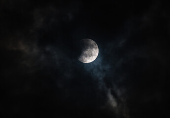 Obraz premium September's full moon, known as the Blood Moon, rises in the sky in Tehatta. As the eclipse begins, a wall of clouds rolls in and obscures the moon, creating various textures in the sky.