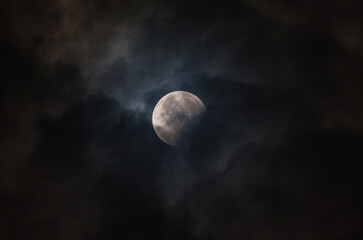 Fototapeta premium September's full moon, known as the Blood Moon, rises in the sky in Tehatta. As the eclipse begins, a wall of clouds rolls in and obscures the moon, creating various textures in the sky.