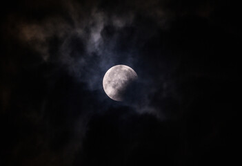 Obraz premium September's full moon, known as the Blood Moon, rises in the sky in Tehatta. As the eclipse begins, a wall of clouds rolls in and obscures the moon, creating various textures in the sky.