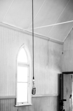 A vintage microphone hanging from the ceiling of a church - monochrome - vertical