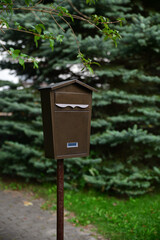 Brown mailbox on a pole on the street near the house