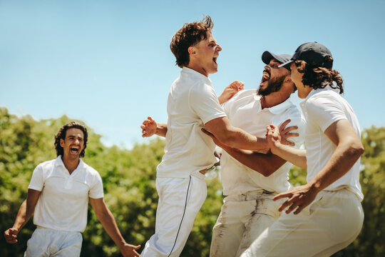 Young male cricket players celebrating a significant victory on the field