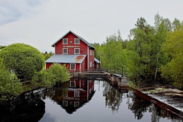 Obraz premium The old wooden Joutsenkoski mill (Joutsekosken mylly) on cloudy spring weather, Ylämaa, Finland.