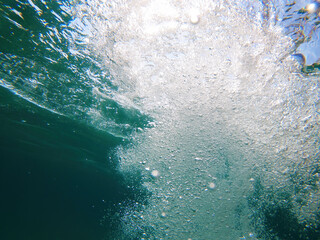 Underwater air bubbles and sunlight in clear ocean water, captured from beneath the surface. Dynamic motion, light rays, and fresh turquoise tones convey a vibrant aquatic atmosphere.