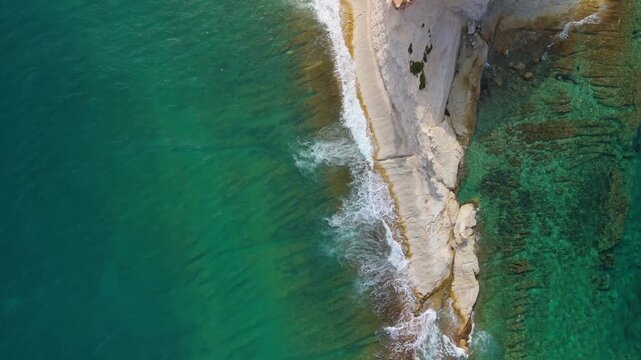 Flying over the steep stretch of the Munxar Path as the crystal clear greenish Mediterranean Sea washes the cliffside in Malta.
