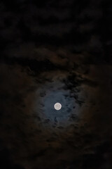 Obraz premium Full moon illuminating dark clouds in a night sky, casting a mysterious and dramatic glow across the scene, offering ample copy space for creative use