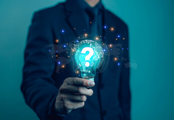 Businessman holding glowing light bulb with question mark symbol and digital world map, representing innovation, problem solving, creativity, global ideas, technology and future business solutions.