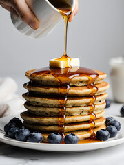 Maple Syrup Being Poured on a Tall Stack of Fluffy Pancakes