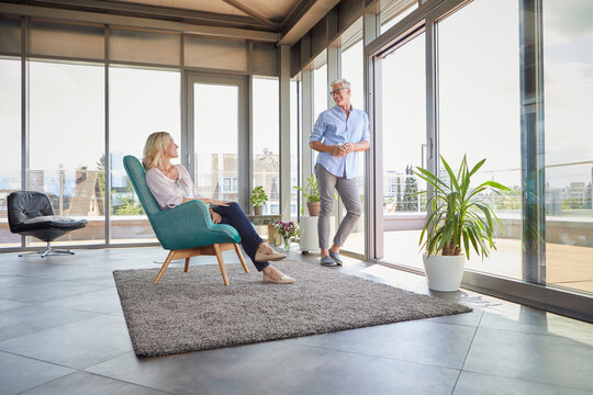 Man and woman enjoying conversation in bright modern loft living room