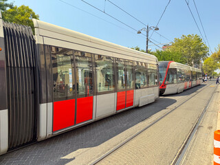Tram with passengers visible through windows at city station platform. Urban transport, daily commute, and public mobility in modern infrastructure.