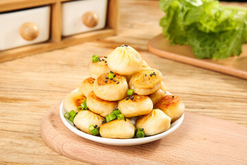 Pan-fried Asian dumplings with green onions and sesame seeds on wooden kitchen table