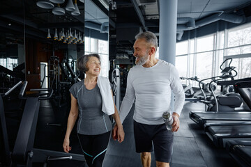 Mature man and woman are having a conversation while resting in a gym