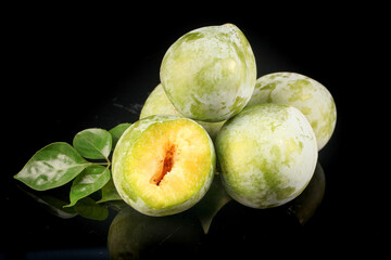 Fresh Green Plums with Yellow Flesh Cut Open on Black Background