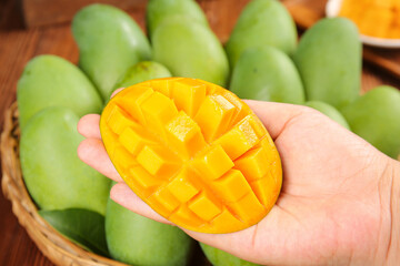 Fresh Cut Mango Half in Hand with Green Mangoes in Basket - Tropical Fruit Food Photography