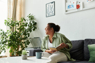 Relaxing afternoon with a joyful woman reading in a modern apartment space
