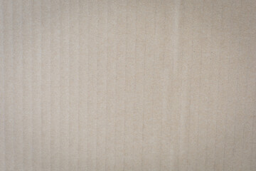 Fototapeta premium Close-up of textured beige corrugated cardboard surface, showcasing vertical ridges and subtle shading.