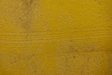 close-up shot of a textured gold yellow concrete surface. The rough and slightly uneven texture, along with subtle variations in the gold yellow hue, creates a visually interesting background.