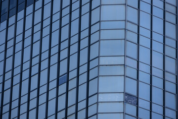 A section of a modern building with many rectangular glass windows reflecting the clear