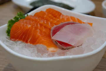 A close-up of a seafood platter with fresh slices of raw salmon, tuna, and white fish