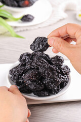 Hand Selecting Dried California Prunes from Bowl - Healthy Air-Dried Fruit Snack