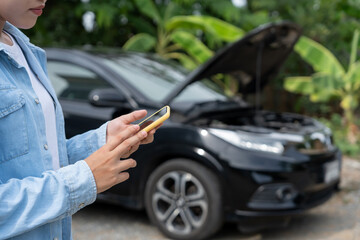 breakdown, broken car, repair. Woman uses mobile phone check insurance premiums through application due to car accident . Find garage to get car fixed during country tour, waiting for help, emergency.