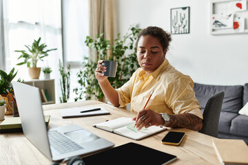 Fototapeta premium Focused woman enjoys remote work while sipping coffee in her cozy apartment