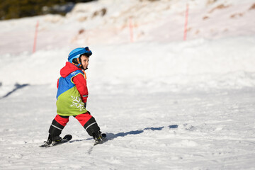 Fototapeta premium Child skiing downhill on sunny winter day