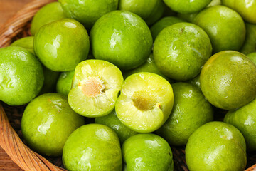 Fresh Green Plums in Wooden Basket with Cut Half Showing Pit - Healthy Organic Fruit Display