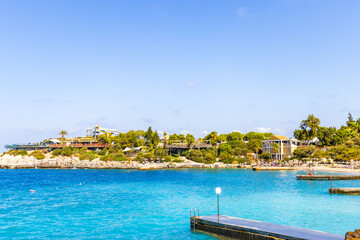 Obraz premium A picturesque seascape with palm trees in the foreground and a rocky coast. Buildings and observation decks are visible on the rock. The azure sea and clear skies create the atmosphere of a resort and