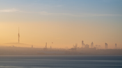 Naklejka premium Evocative, romantic early morning image of the Bosphorus, with the sunrise penetrating the morning mist, the Camlica Tower visible on the horizon, Istanbul Turkey
