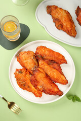 Crispy Golden Fried Chicken Wings with Fresh Garnish and Orange Juice on Green Background