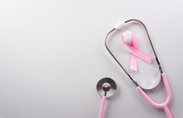 Pink ribbon and stethoscope on paper background for supporting breast cancer awareness month campaign.