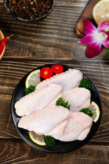 Raw Chicken Wings with Lemon and Herbs on Black Plate - Fresh Poultry Meat Ready for Cooking