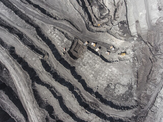 Panoramic aerial view of coal mine. Open pit mine industry, big yellow mining truck for coal quarry. Open coal mining anthracite mining. Pit on coal mining by open way. Rock loading in trucks.
