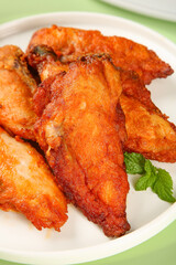 Crispy Spiced Chicken Wings with Golden Brown Skin on White Plate with Fresh Mint Garnish