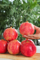 Fresh Red Pomegranates with Soft Natural Highlights on Wooden Surface Against Green Background