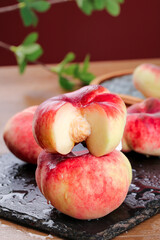 Fresh Ripe Peaches Cut in Half on Slate Board Closeup Display with Green Leaves